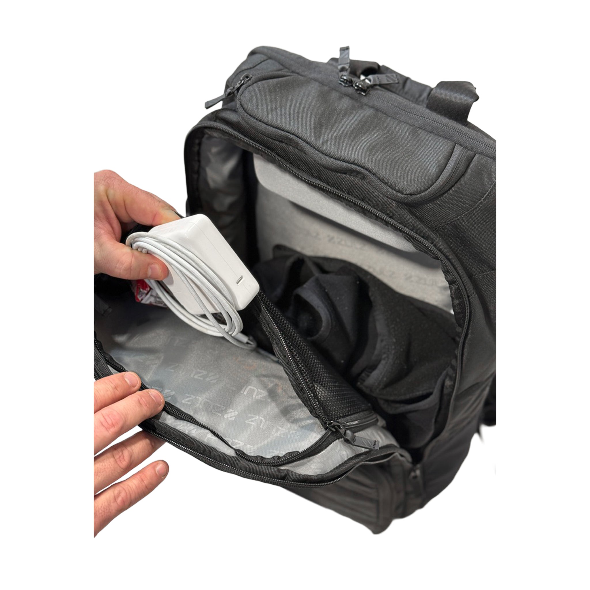 Black backpack with a hand placing a white charger inside