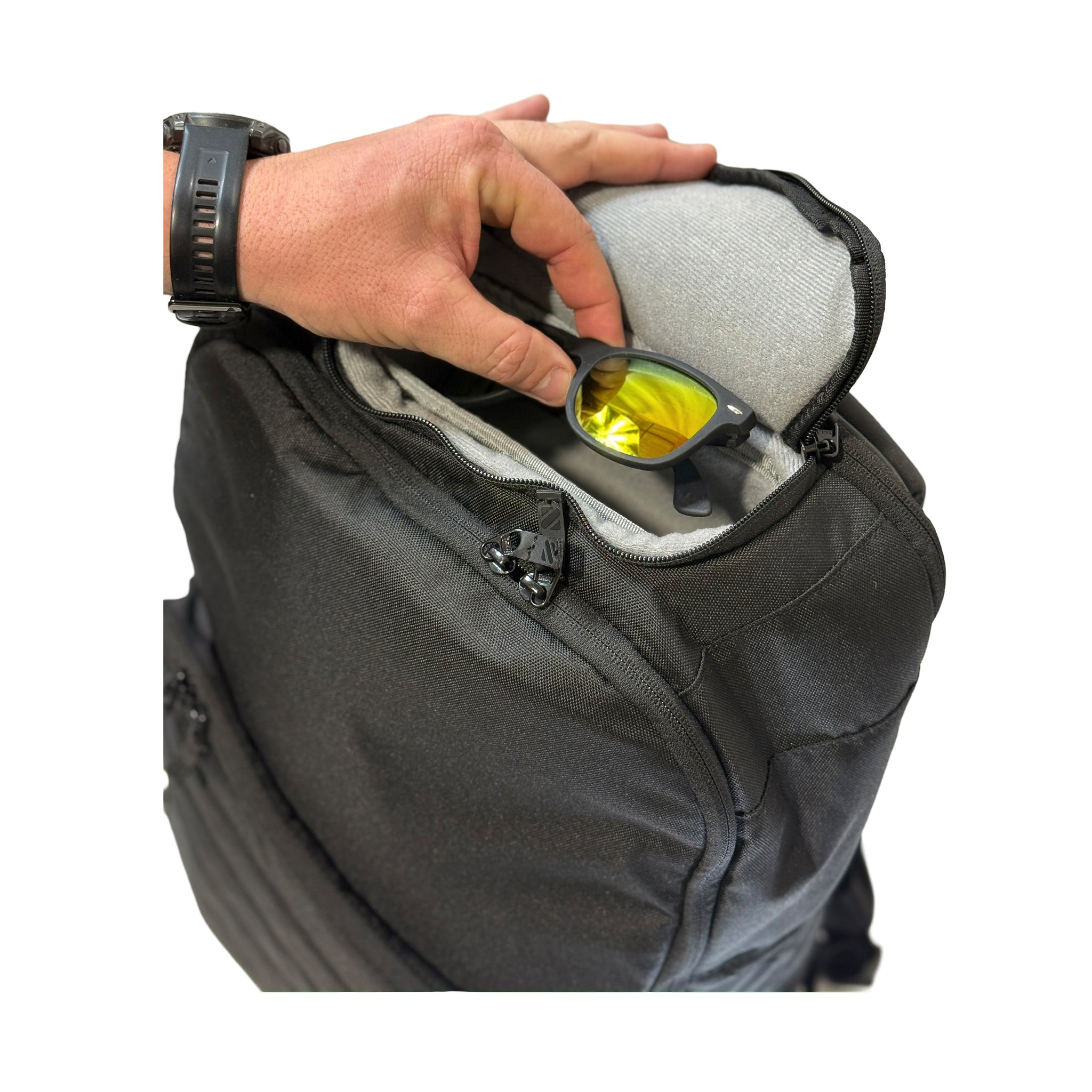 Person placing sunglasses into a backpack pocket on a white background